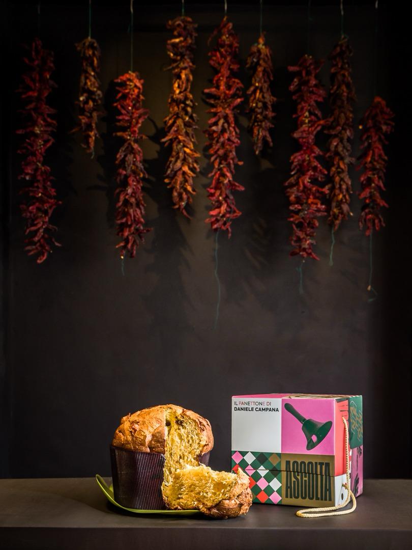 Panettone di Daniele Campana alla 'nduja di Suino Nero, amarena e cioccolato, tagliato, accanto alla scatola regalo